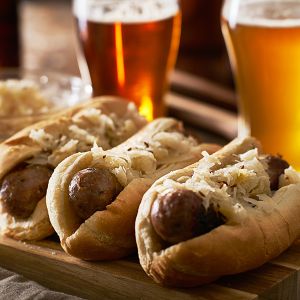 Brats in buns in a row with beers behind them