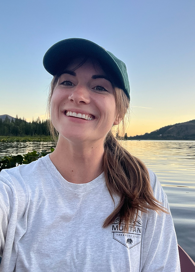 Sierra Bradtz in a canoe on a lake with a the sun setting behind her